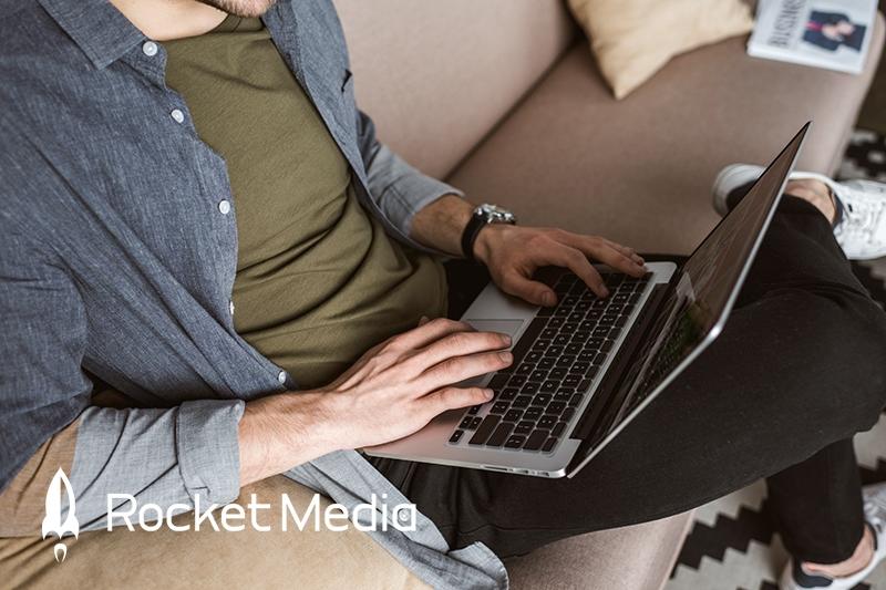 Man sitting on couch typing a blog